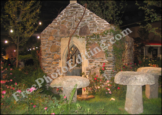 This is a photo of an old cottage in Ireland by night. There is a garden outside that has table-height toadstools made out of roughly carved stone.