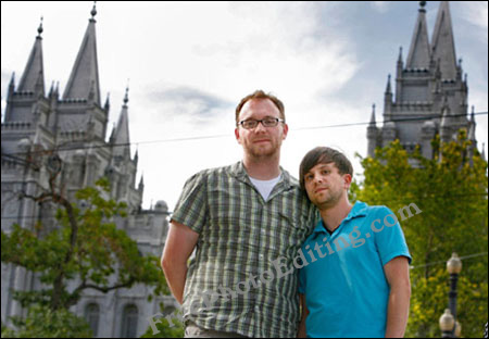 Gay couple on holiday, may be in France. They have been photographed against beautiful church-like buildings, probably a hundred years old. A few power lines can be seen running across the breadth of the photo
