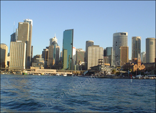 Photo editing required: This is a photograph of the Sydney skyline with the Circular Quay in foreground. A shark-in-water scenario needs to be created in the waters.