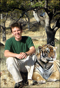 This is a photo editing example in which a tiger has been accommodated beside a young man photographed in a wildlife park.