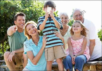 Photo editing example [Edit person in group]: This is a family group photograph spanning three generations. The little boy is holding a cell phone to his face, covering his eyes entirely. The challenge is to move the cell phone down and bring his eyes into view! Open eyes at that!