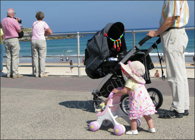 Photo editing services to change background in photo. This is a photo of a little girl walking with her grandfather along the Bondi Beach in Sydney, Australia. The job is to change the background to a nature photo with a lot of trees. The photo after background chnage can be seen below.