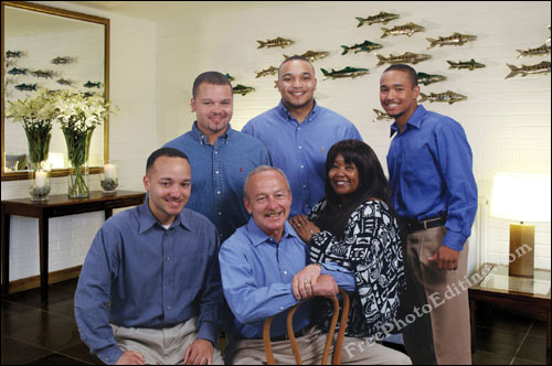 Studio background used in family photograph has been replaced. Photograph has been edited such that the group is now in a bright living room.