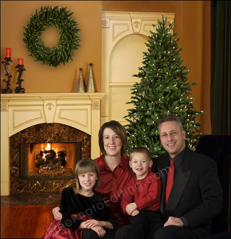 Photo editing, photo retouching sample: The family seen in this picture was originally photographed in a studio against a plain cloth background. They have now been placed in an elegant living room with a beautiful Christmas tree and other xmas decorations. (The original unedited photo can be seen above.)