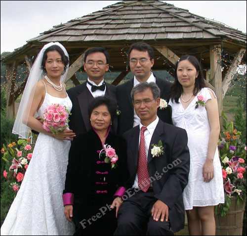 Wedding photograph showing bridal couple, parents and another young couple. Note that the bride is much taller than her new husband.