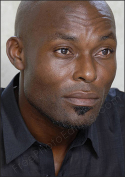 This is a photo of a black man with a serious and sad expression on his face. His expression needs to be softened to look less intense and even a bit pleasant. The retouched photo can be seen on right.
